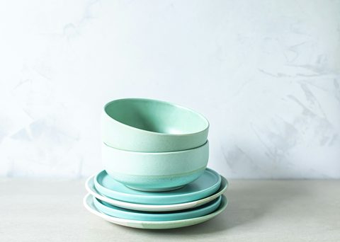 Bowls y platos de cerámica verde claro apilados.