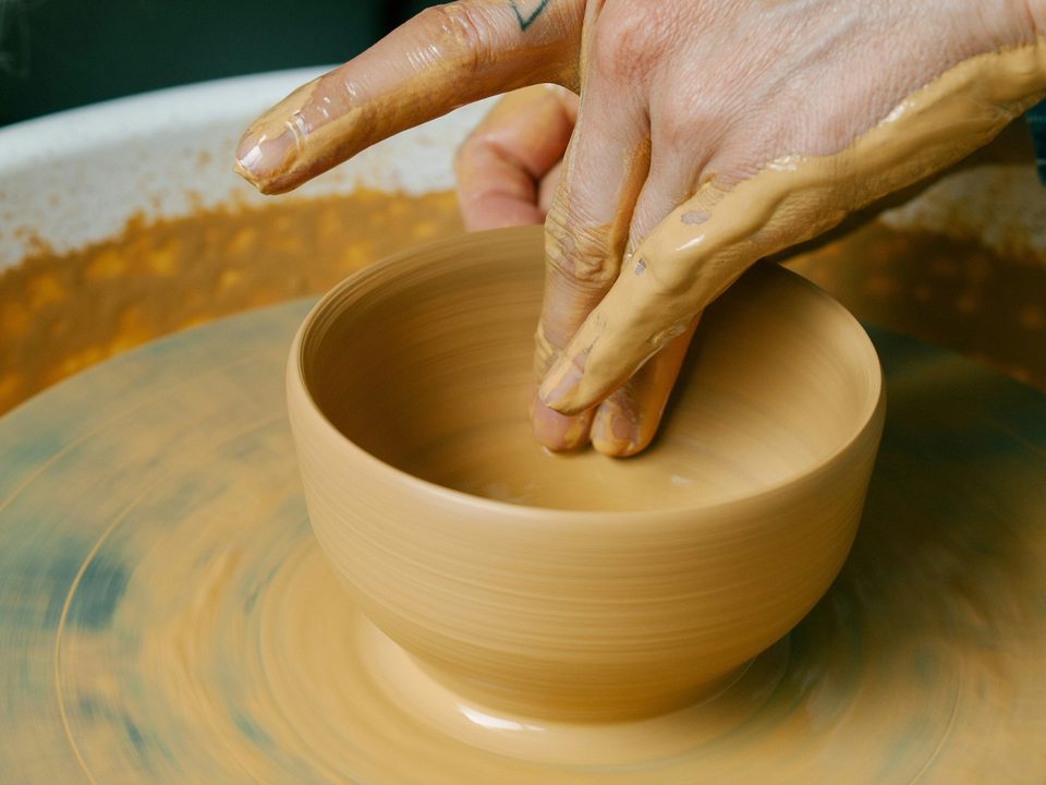 Manos con barro dando forma a un bowl en el torno. (en el torno)
