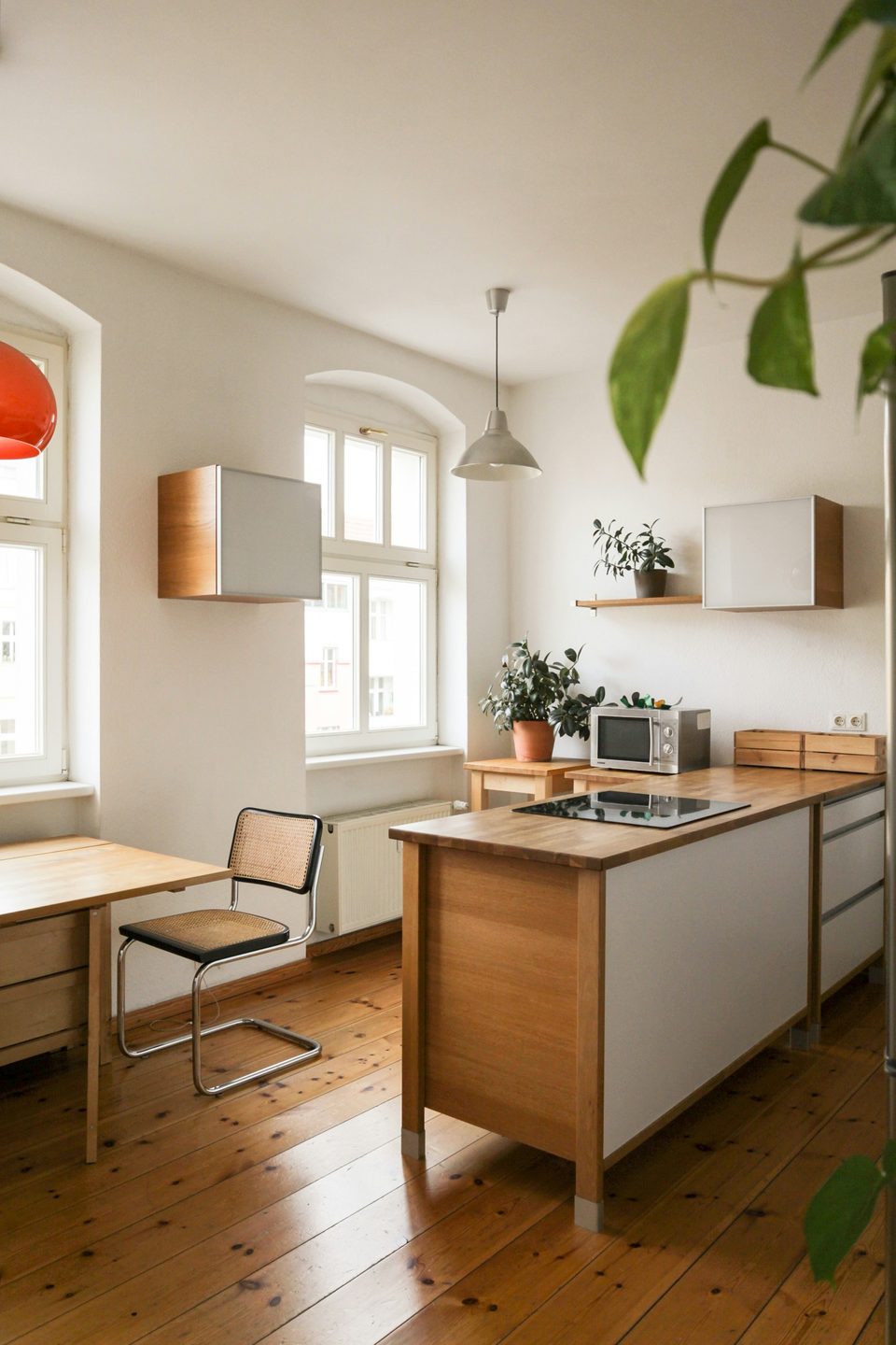 Cocina con una isla de madera de frente blanco, piso de tablas y ventanas en arco que dejan entrar la luz natural.