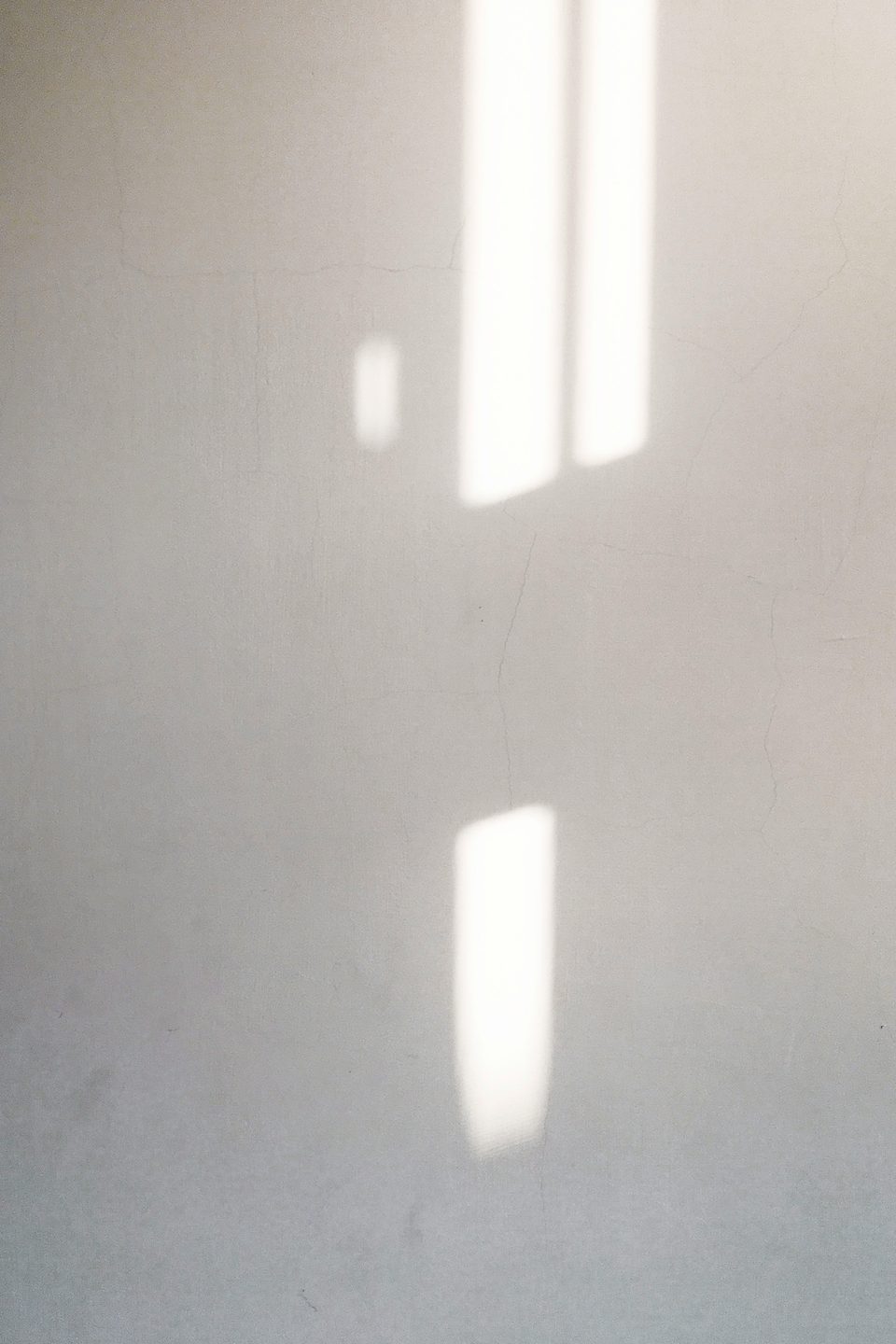 Rectángulos de luz de sol proyectados sobre un muro claro.