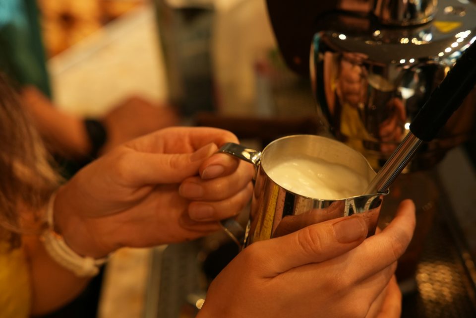 Barista preparando café en la barra, junto a la máquina de espresso.